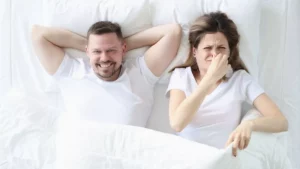 Homme rigolant, tandis que la femme se bouche le nez