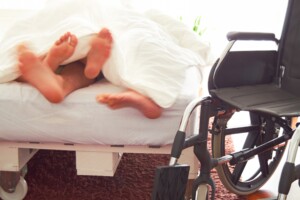 Des pieds dépassant d'un lit avec un fauteuil roulant à côté